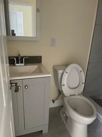 a bathroom with a granite countertop toilet sink and mirror