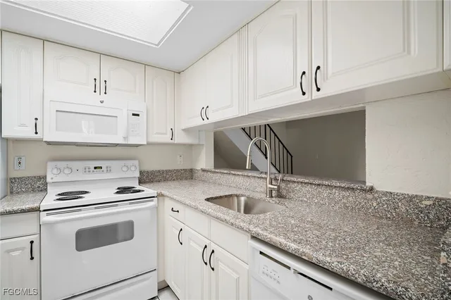 a kitchen with granite countertop white cabinets and white appliances