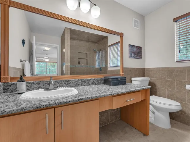 a bathroom with a granite countertop sink a toilet and mirror