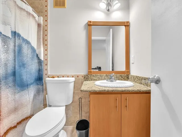 a bathroom with a granite countertop sink toilet and mirror