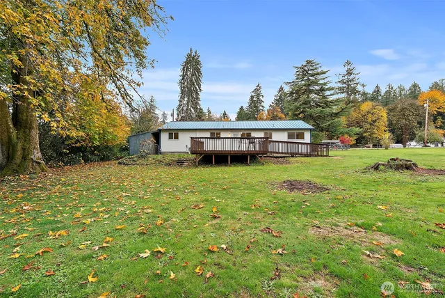 a view of a house with a big yard and large trees