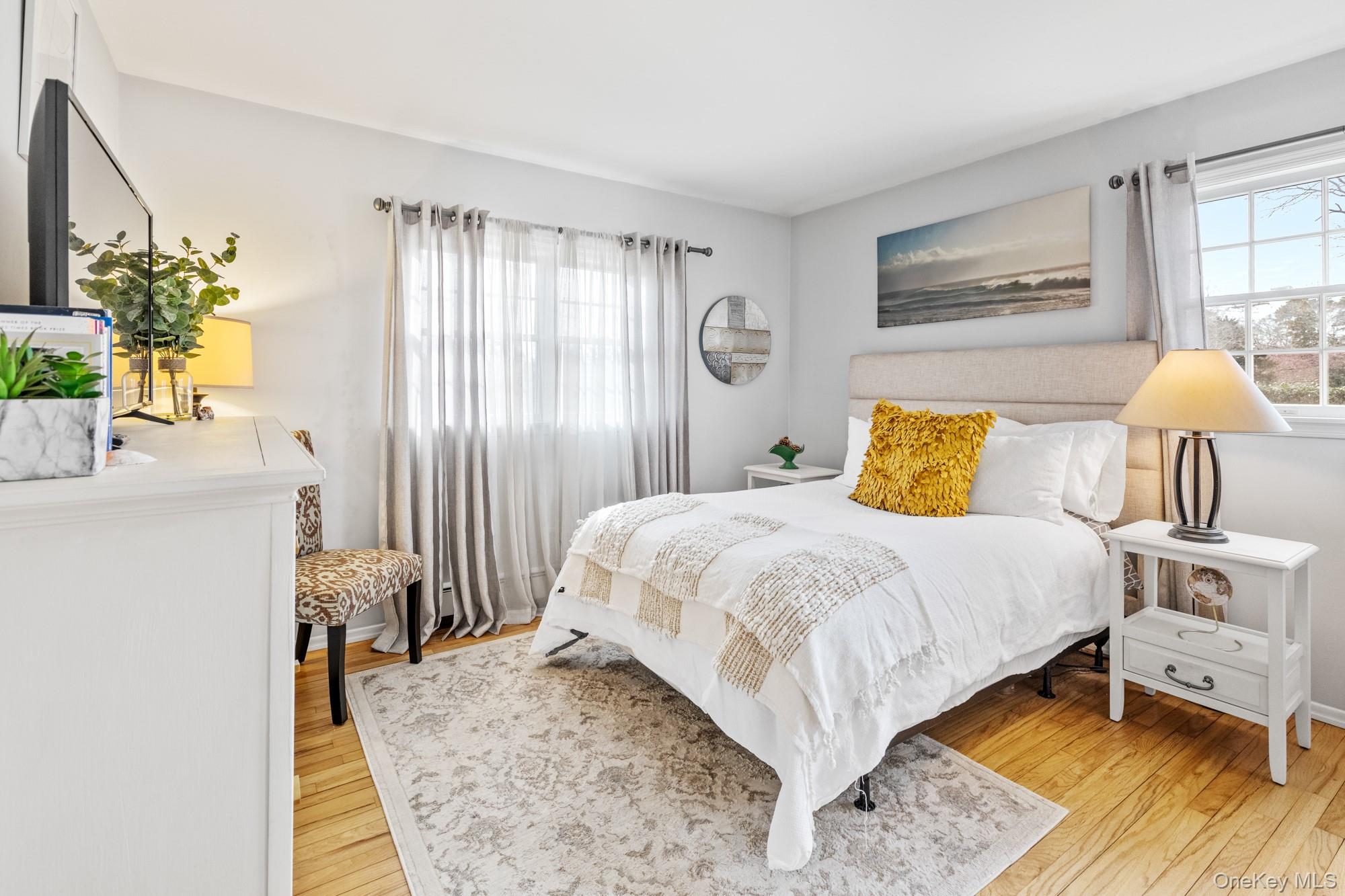 79 East Tiana Road Hampton Bays, NY 11946 - Photo 17 of 26 a bedroom with a bed table flowerpot and window