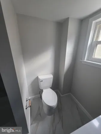 a white toilet sitting in a bathroom next to a window
