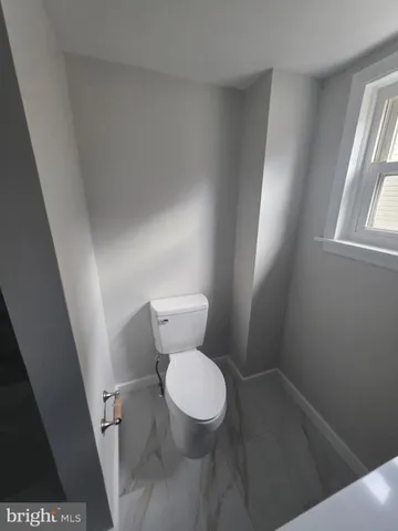 a white toilet sitting in a bathroom next to a window