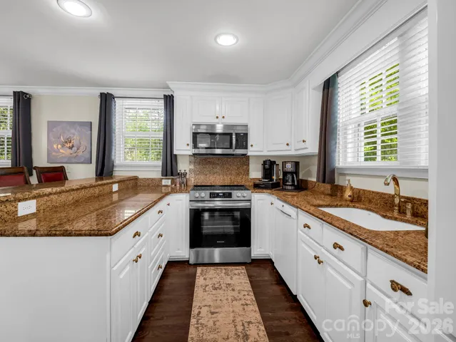 a kitchen with granite countertop a sink stove and cabinets