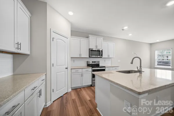 a kitchen with stainless steel appliances granite countertop a refrigerator sink and white cabinets