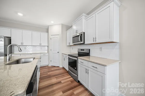 a kitchen with white cabinets sink and stainless steel appliances