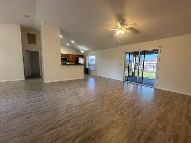 a view of an empty room with window and wooden floor