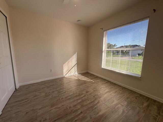 519 Southwest Laconic Avenue Port St. Lucie, FL 34953 - Photo 5 of 10 an empty room with wooden floor and windows