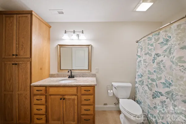 a bathroom with a granite countertop toilet sink and mirror