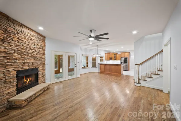 a view of an empty room with wooden floor fireplace and a window