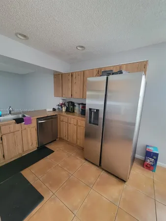 a kitchen with stainless steel appliances granite countertop a refrigerator a sink a stove top oven and a counter space