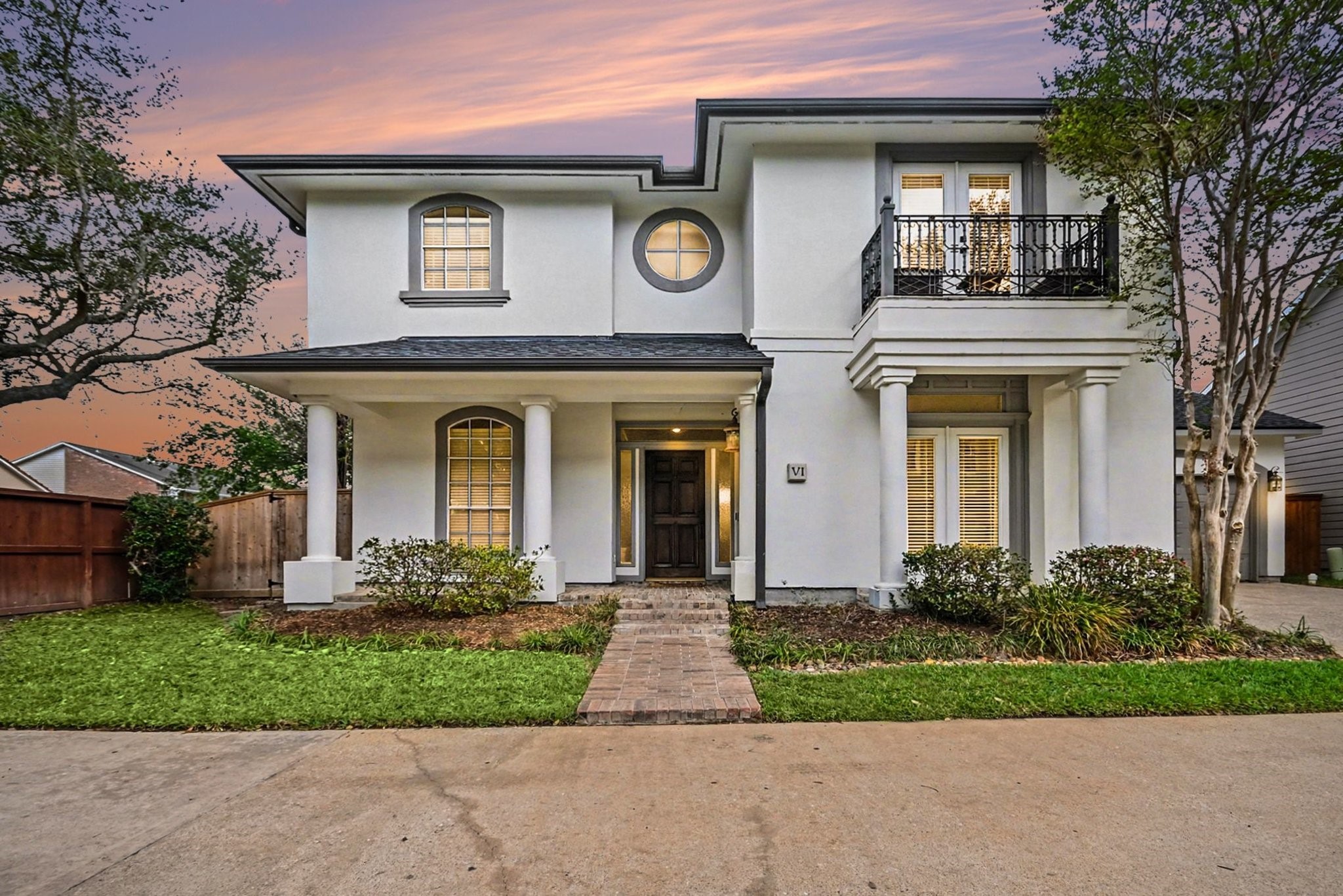 Charming two-story home with elegant columns, a balcony, and a welcoming entrance.