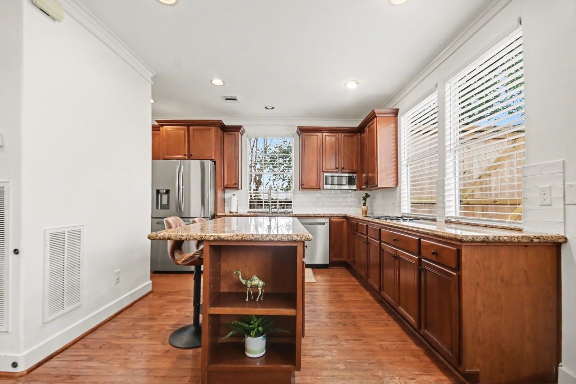 1470 Springrock Lane, Unit 6 Houston, TX 77055 - Photo 7 of 32 a kitchen with stainless steel appliances granite countertop wooden cabinets a sink dishwasher a stove and a refrigerator with wooden floor
