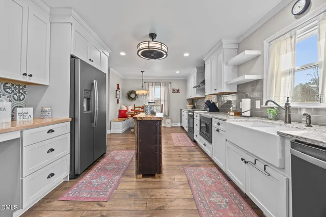 a very nice looking kitchen with granite countertop a stove two chairs and wooden floor