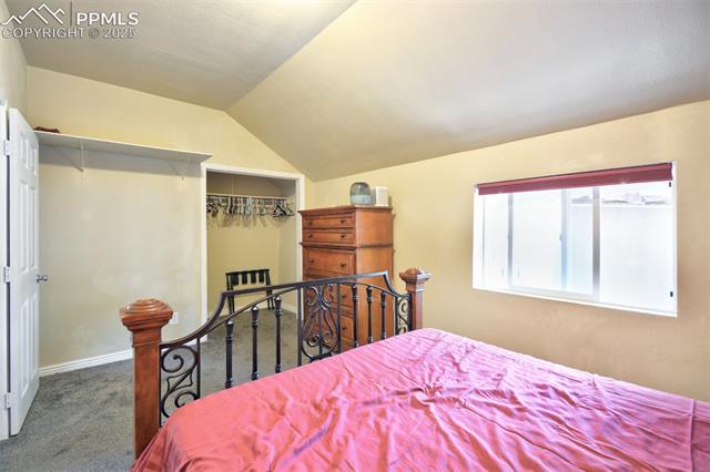46 Sunflower Road Colorado Springs, CO 80907 - Photo 21 of 35 Carpeted bedroom featuring vaulted ceiling, a closet, and baseboards