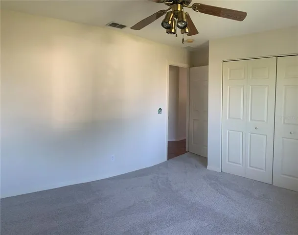 a view of a small space with wooden floor a chandelier fan and windows