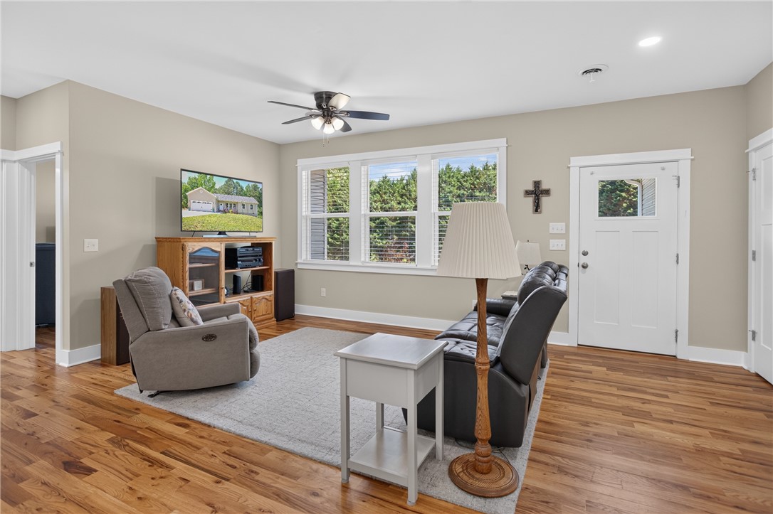 405 Pawnee Drive Walhalla, SC 29691 - Photo 7 of 36 Well-lit living room with natural wood flooring and multiple windows framing tree views.