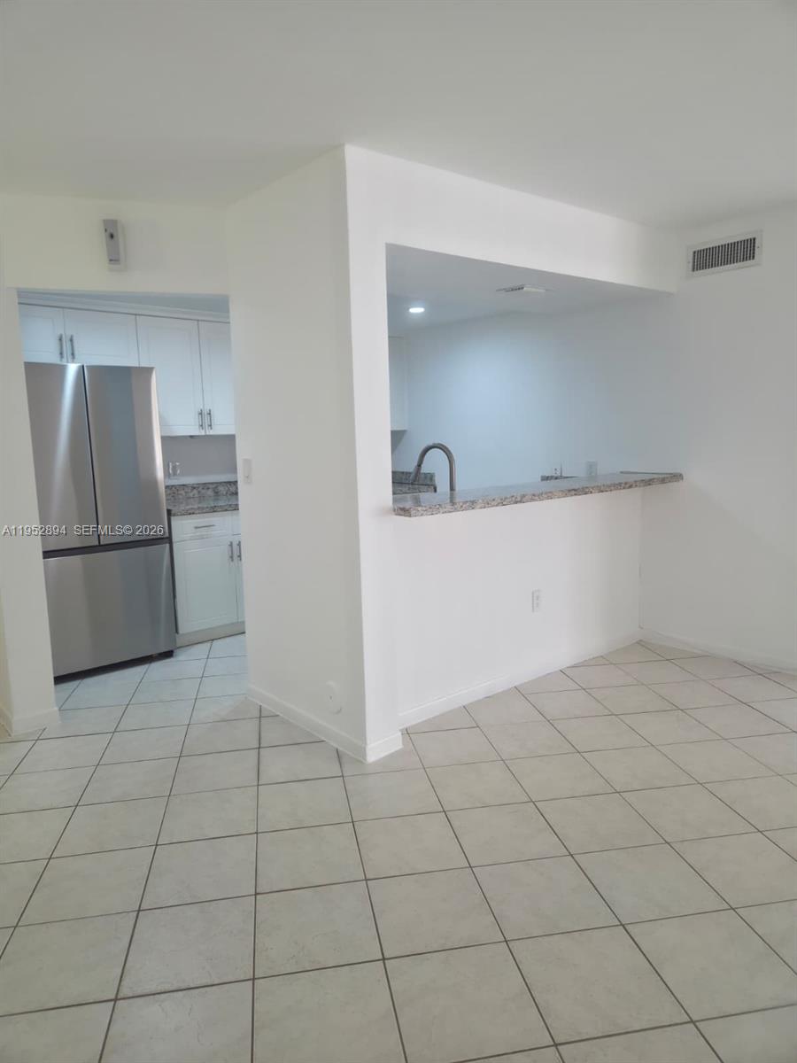 7075 Northwest 186th Street, Unit C104 Hialeah, FL 33015 - Photo 2 of 24 a view of a refrigerator in kitchen and an empty room