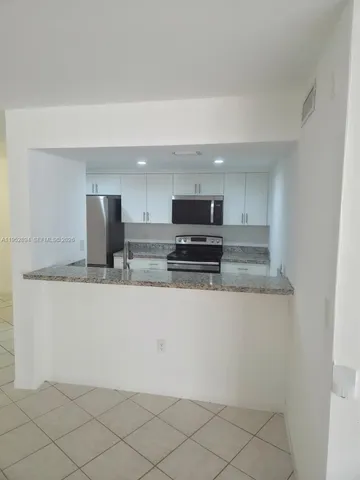 a kitchen with granite countertop white cabinets and stainless steel appliances