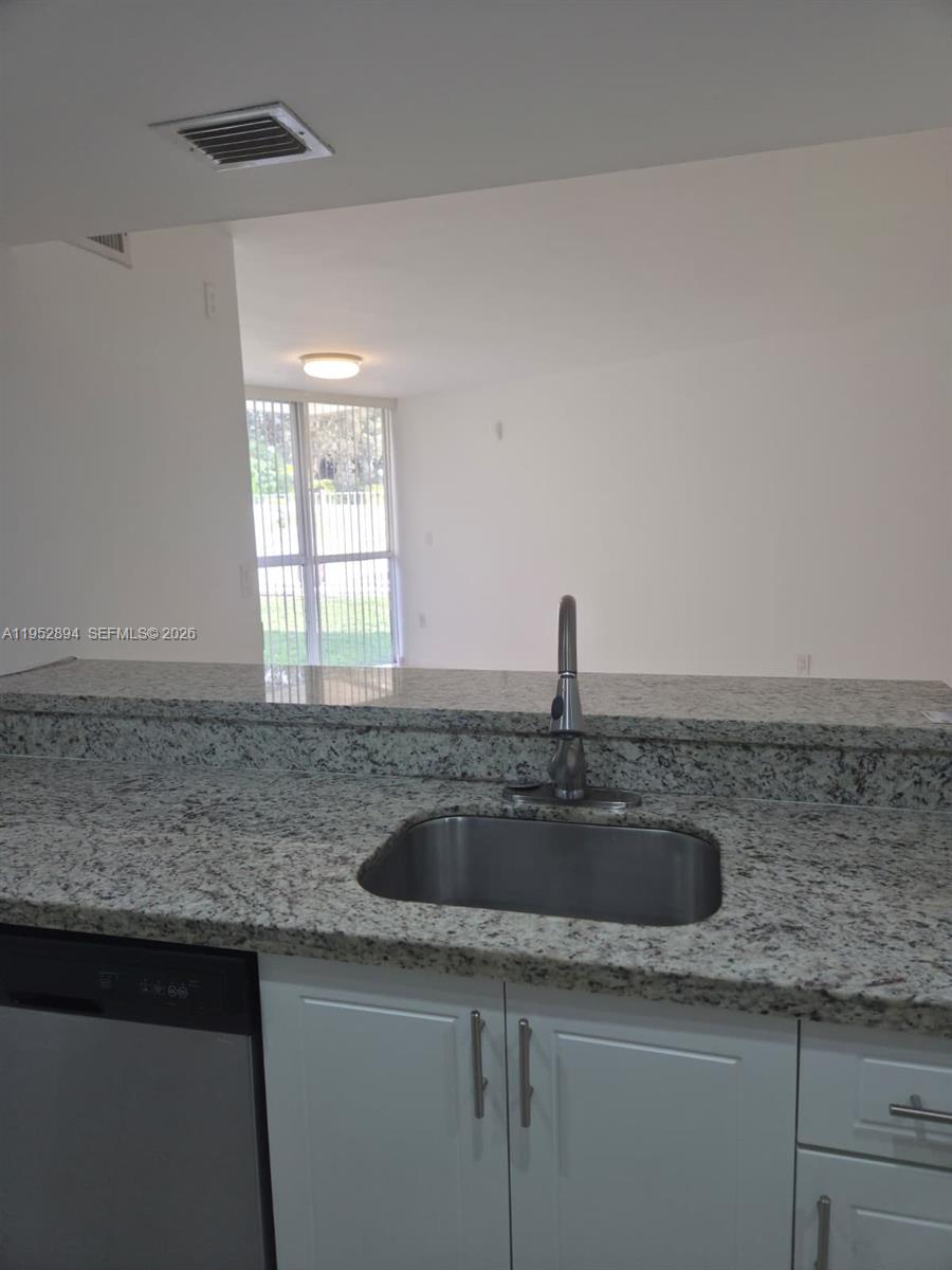 7075 Northwest 186th Street, Unit C104 Hialeah, FL 33015 - Photo 4 of 24 a kitchen with granite countertop a sink and a window