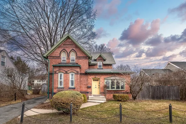 a front view of a house with large trees