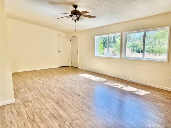 a view of an empty room with wooden floor and a window