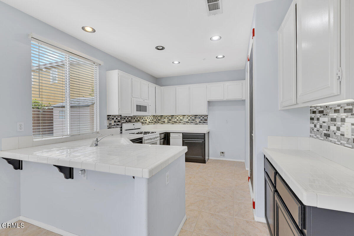825 Noontide Way Oxnard, CA 93035 - Photo 8 of 26 a kitchen with granite countertop a sink stainless steel appliances and white cabinets