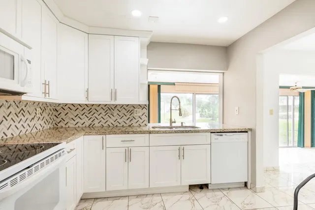 a kitchen with granite countertop white cabinets and sink