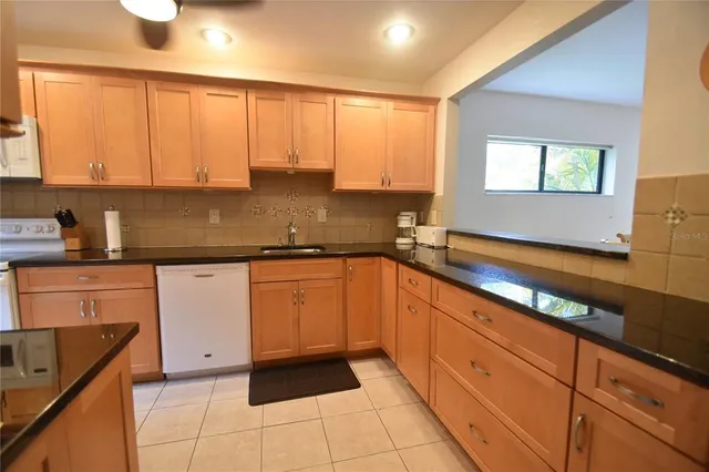 a kitchen with granite countertop a sink a stove top oven and cabinets