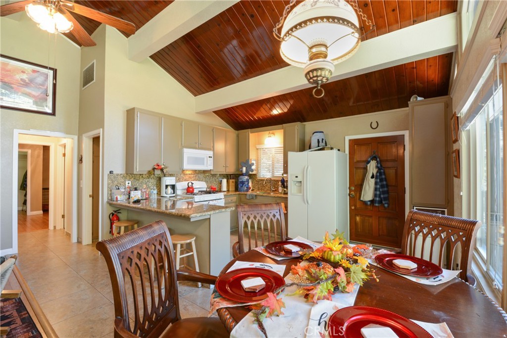 1942 Wilderness Road Running Springs, CA 92382 - Photo 11 of 20 a kitchen with stainless steel appliances granite countertop a refrigerator a stove top oven a dining table and chairs with wooden floor