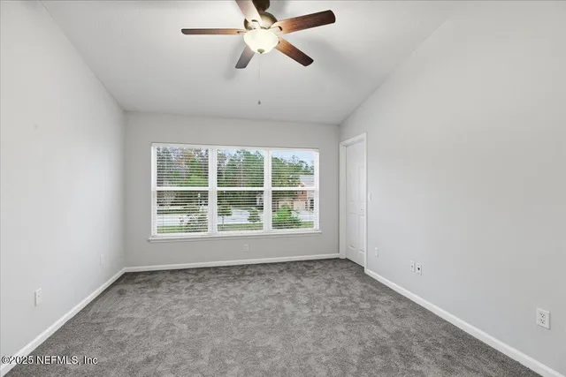 an empty room with a window and a fan