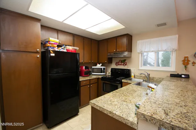 a kitchen with granite countertop a refrigerator stove and sink