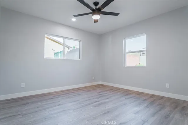 a view of empty room with wooden floor and fan