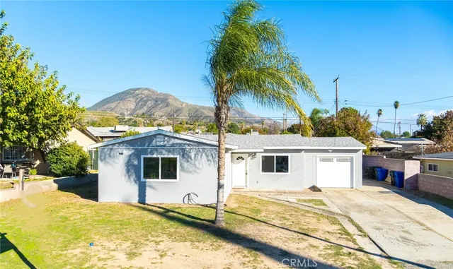 a white house with a large pool and lawn chairs under an umbrella