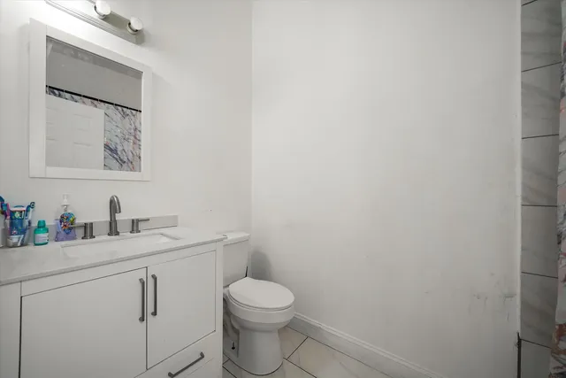 a bathroom with a toilet sink vanity and mirror