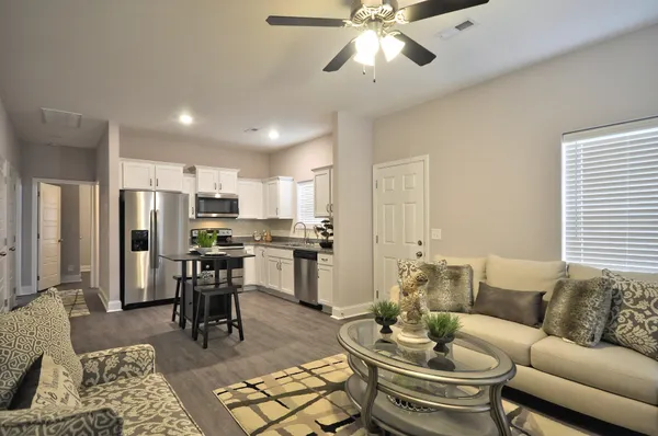 a kitchen with stainless steel appliances a dining table chairs refrigerator and cabinets