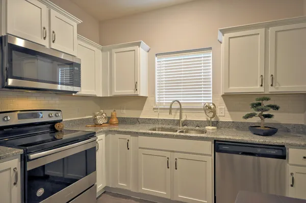 a kitchen with granite countertop a sink stove and microwave
