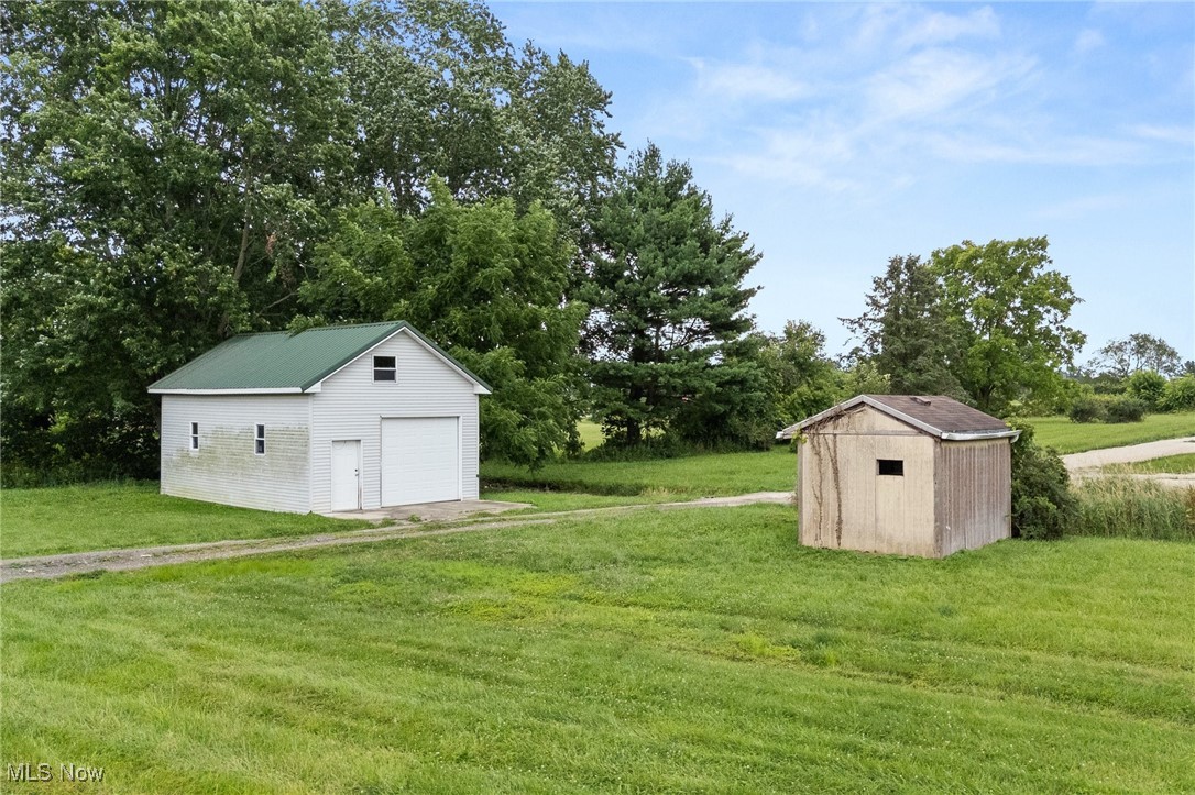4838 Angling Rd Extension Wooster, OH 44691 - Photo 5 of 39 View of grassy yard with an outdoor structure, a garage, and view of wooded area