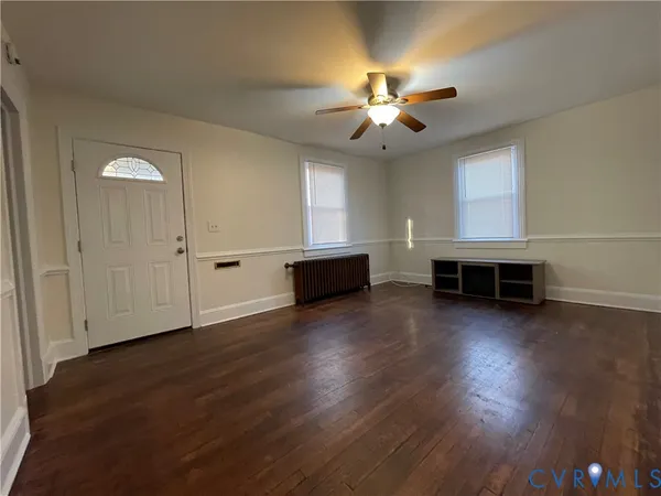 an empty room with wooden floor chandelier fan and windows