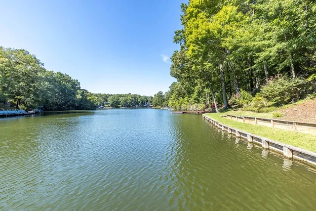a view of a lake with table and chairs potted plants