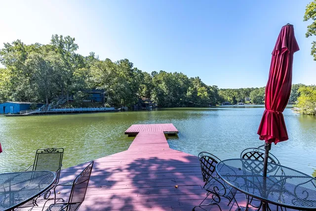 a view of a lake with table and chairs potted plants