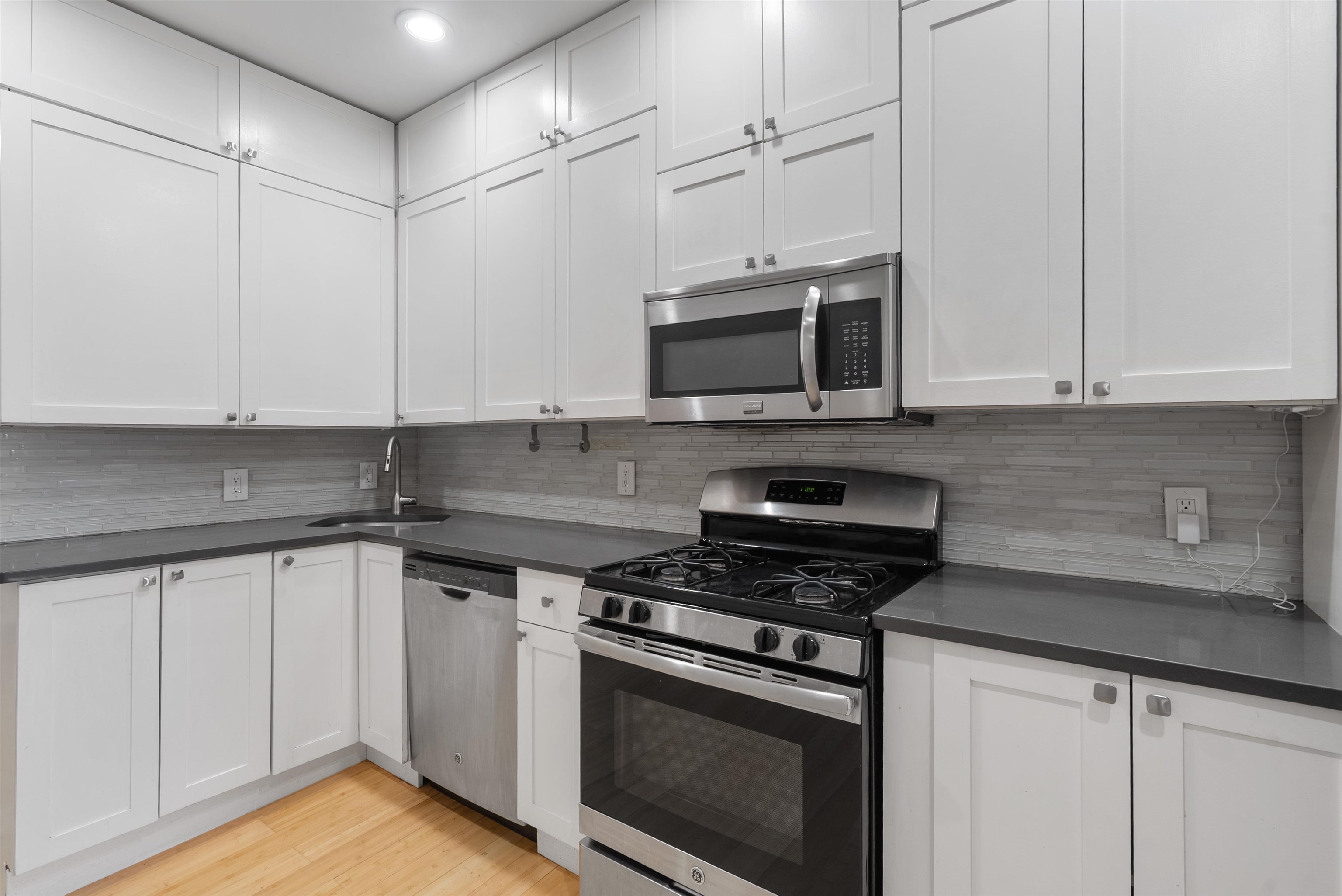 809 Park Avenue, Unit 9 Hoboken, NJ 07030 - Photo 8 of 30 a kitchen with stainless steel appliances granite countertop a stove a microwave and white cabinets