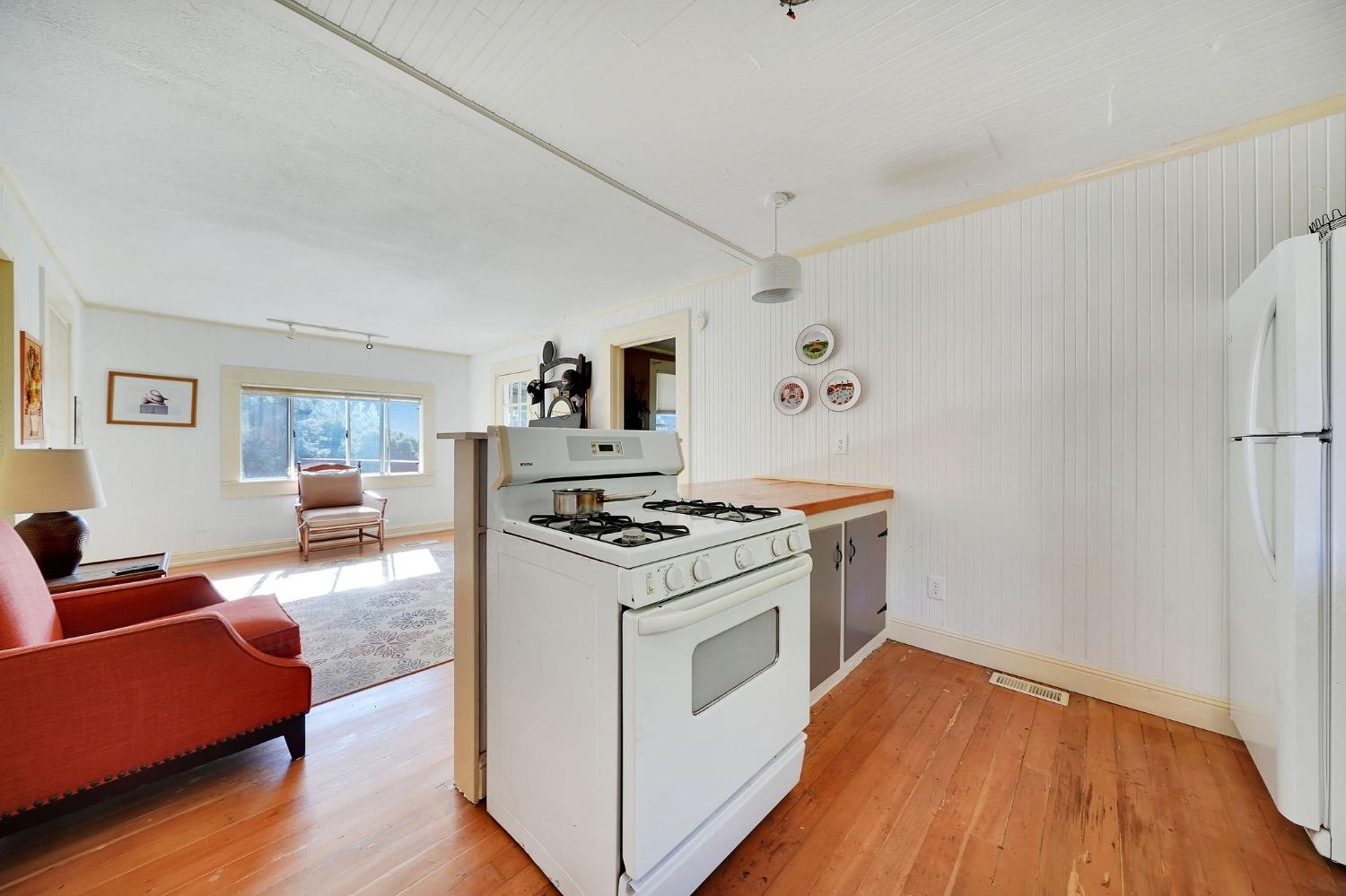 15579 Jesus Maria Road Mokelumne Hill, CA 95245 - Photo 56 of 91 a kitchen with wooden floors and white stainless steel appliances
