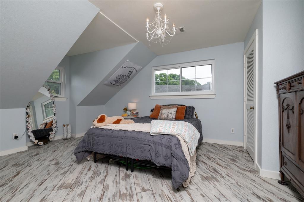 8948 David Fort Road Argyle, TX 76226 - Photo 28 of 39 Attic bedroom featuring pitched ceilings, wood-finish flooring, multiple windows, a louvered bi-fold door, and a decorative chandelier