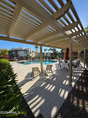 a view of a patio with table and chairs under an umbrella with a large tree