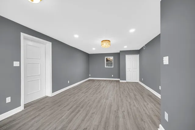 a view of an empty room with wooden floor and closet