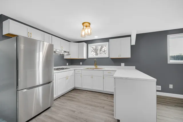 a kitchen with a sink a stove a refrigerator and white cabinets