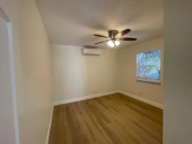 an empty room with a chandelier fan and a window