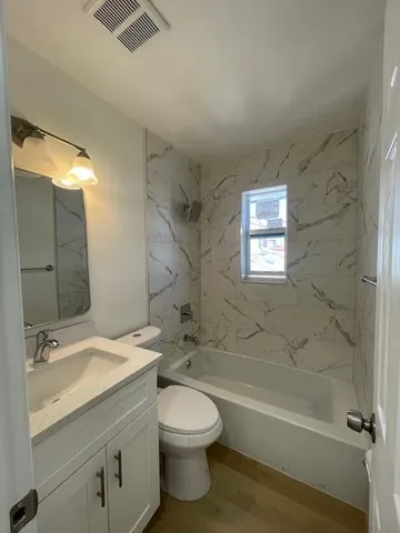 a bathroom with a granite countertop toilet a sink and bathtub